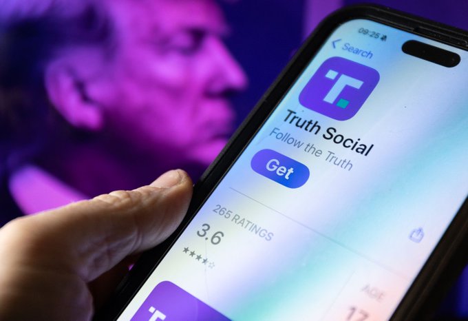 A hand holds a smartphone displaying the Truth Social app download page with 'Follow the Truth' tagline and a 3.6 star rating, with a man visible in the purple-lit background.