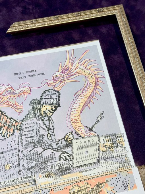 A mixed-media art print featuring a soldier and dragon illustration surrounded by typewriter text, signed by the artist and titled 'METRO BOOMIN WANT SOME MORE,' displayed with an ornate gold frame on a purple velvet background.