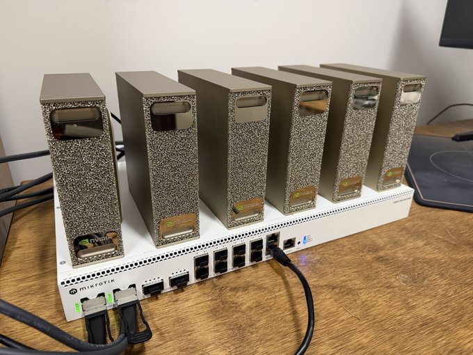 A home mining or computer setup featuring six metallic gold cryptocurrency miners stacked on top of a MikroTik networking switch/router with multiple ethernet cables plugged in.