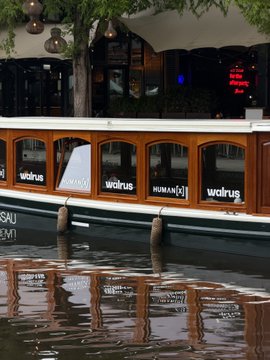 The image shows a boat named "WALRUS" floating in the canal of Amsterdam, branded with "walrus" and "HUMANX" logos on its side. The accompanying post highlights the Walrus team's presence at the HumanX conference in Amsterdam, using the boat as a creative, on-brand touchpoint to promote their "Walrus Memory" solution for AI systems at the event.