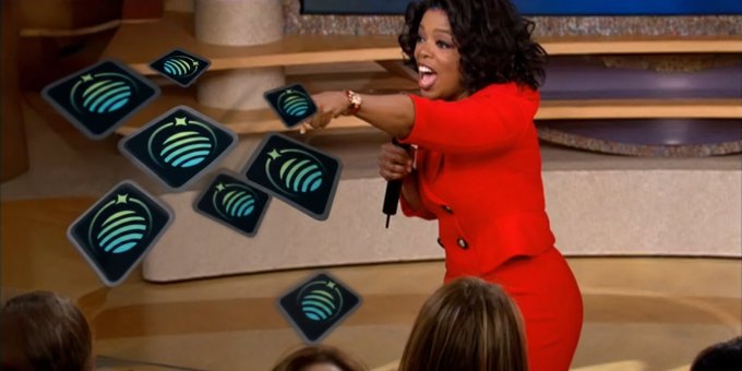 A woman on stage in a red outfit animatedly tosses a handful of square badges featuring a blue globe/star logo to an audience. The badges visually represent the "top predictor" awards referenced in the post, with their scattered, mid-air motion emphasizing the celebratory distribution of these recognition items.