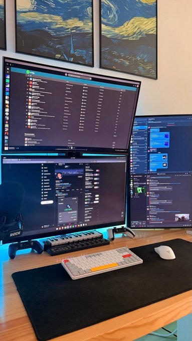 A multi-monitor computer setup displaying chat interfaces and messaging apps, accompanied by a Rode microphone, compact mechanical keyboard, and mouse on a wooden desk. The "GOOD MORNING DROP YOUR ADDRESS" caption suggests the streamer is inviting viewers to share their location for potential meetups or community interaction.