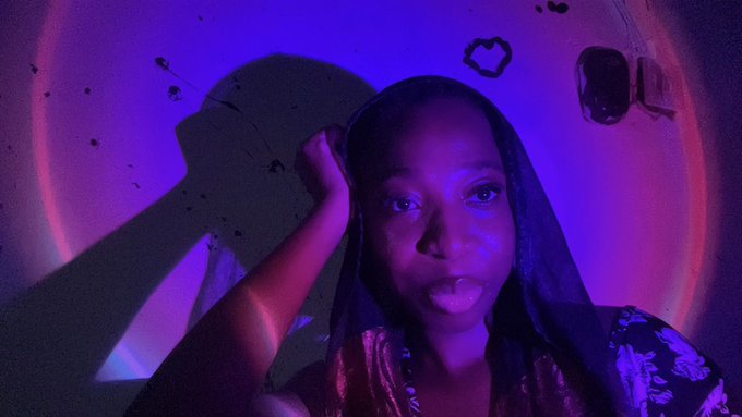 The image features a woman with long hair wearing a black headscarf, posing for a photo against a purple background. The woman's hand is placed on her face as she looks directly at the camera. The caption of the image reads "good morning wonderful believers go to church hit my pinned, upskill and mind yo business $RIVER teased the beginning of S6, will you be showing up?". This message seems to be related to a post about faith or spirituality, possibly encouraging followers to attend church services regularly.