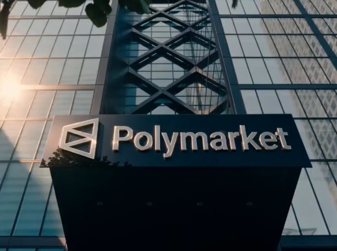 A low-angle photograph of a building entrance with a 'Polymarket' sign featuring its triangular logo, with sunlight flaring through the glass windows.