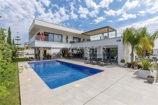 A modern luxury villa with a swimming pool, outdoor patio, and contemporary architecture featuring 'KAISER PROPERTIES' watermark.