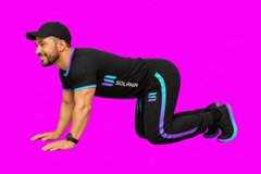 A man in black Sculp athletic wear demonstrating an exercise position on all fours against a bright pink background.