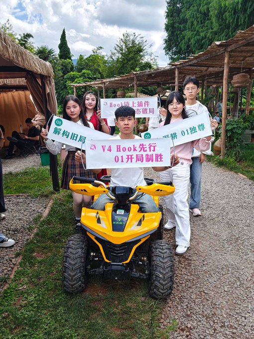 A group of young people in China pose together around a yellow ATV, holding promotional banners reading "V4 Hook先行 01开局制胜" (V4 Hook leads, 01 wins from the start) and "Hook链上插件 突破局 01独尊," celebrating the excitement around the V4 Hook and 01 token launches. The image ties directly to the post's reference to China showing enthusiasm for these blockchain projects.