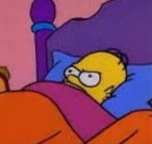 A still from The Simpsons showing Homer Simpson lying in bed with half-open eyes and a tired, unamused expression under pink covers.