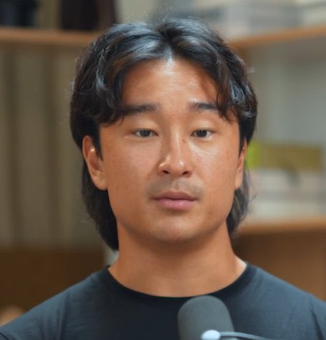 A man with medium-length dark hair and a neutral expression appears to be speaking into a microphone in what looks like a podcast or interview setting. The image likely accompanies a critical post about Fomo's user base, suggesting the speaker is addressing concerns about the platform's inflated user numbers and their reliance on inexperienced traders being exploited.