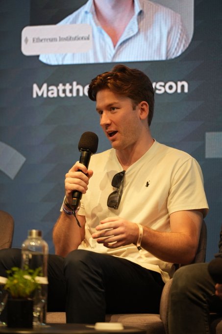 Matthew Dawson from Ethereum Institutional speaks into a microphone at a panel, with his name displayed on the screen behind him alongside the Ethereum Institutional logo, illustrating the article's point about institutional blockchain adoption and infrastructure.