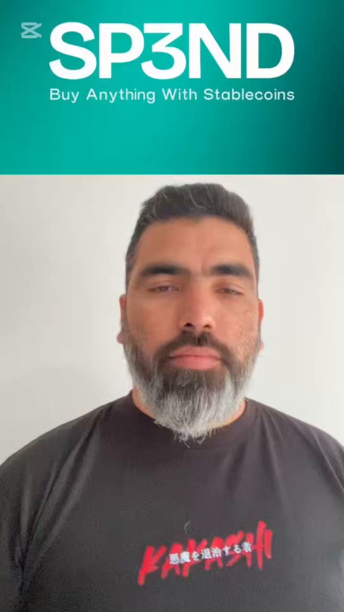 The image features a man wearing a black t-shirt with red text that says "KAKAISHI" printed on it. The man has a beard, and he appears to be posing for a picture. In the background of the photo, there is an advertisement for Amazon, which includes a link to buy anything from Stablecoins.