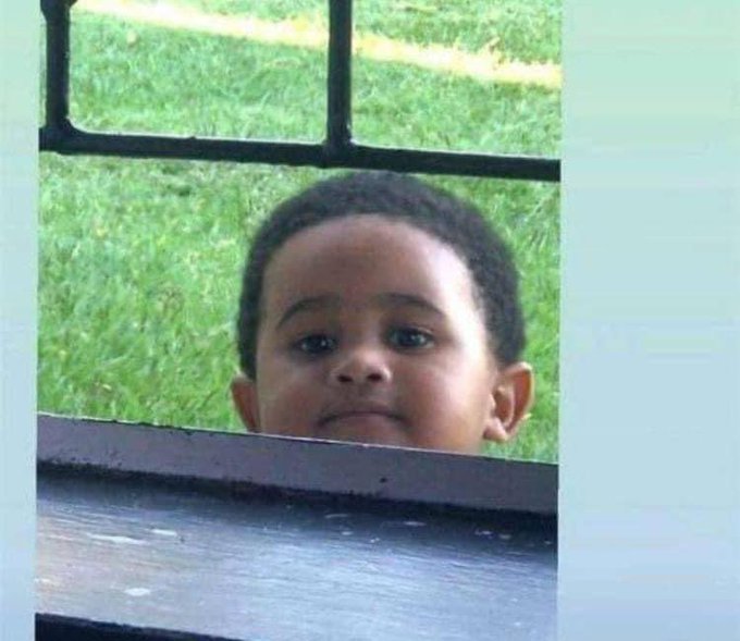 A curious young boy peeks over a wooden ledge, his wide eyes and raised eyebrows suggesting anticipation, mirroring the post's sense that something exciting is being "cooked" within the Base ecosystem.