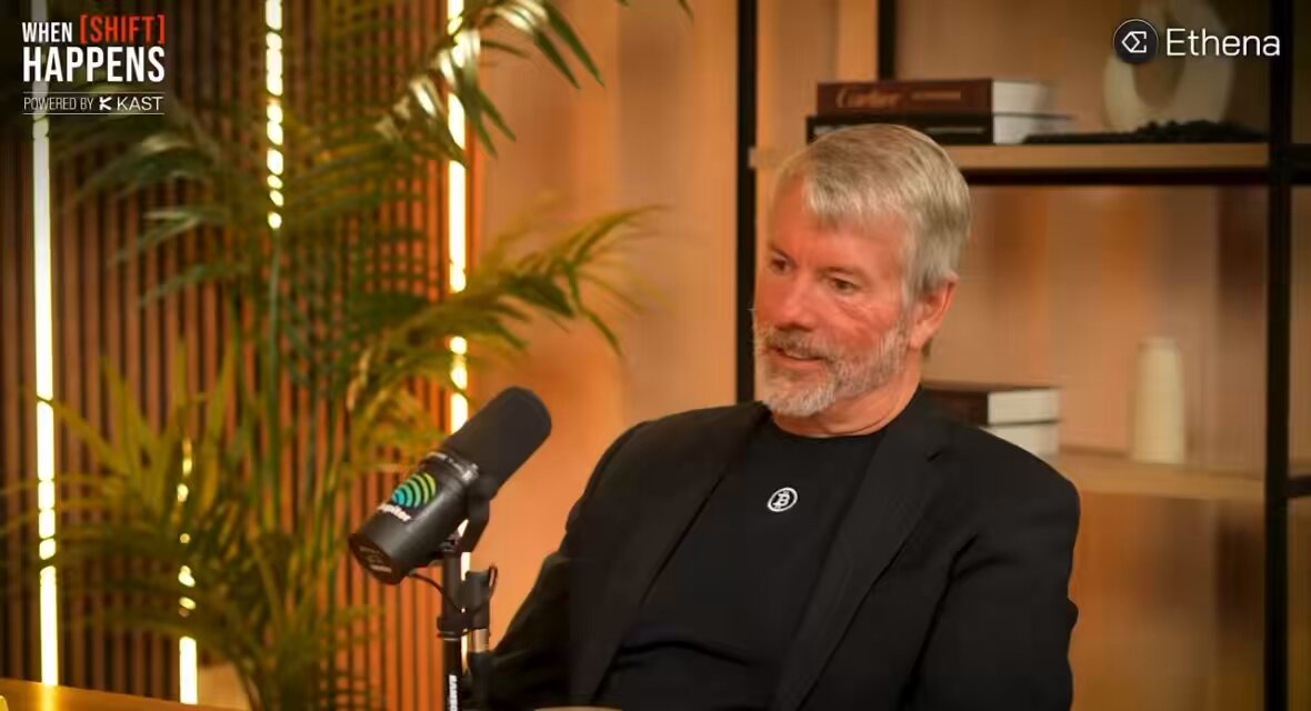 The image shows a man wearing a black suit sitting behind a microphone, talking into it during an interview or podcast recording session. The background features a bookshelf filled with various books, suggesting that he might be discussing topics related to finance, technology, or other intellectual subjects. The caption on the image reads "michael saylor on what bitcoin's price would be if he never started buying somewhere between $10,000 and $80,000 it wouldn't be as high as it is right now." This implies that the man might be discussing the potential impact of Bitcoin's value on its current market position.

The image also contains a plant in the background, adding some greenery to the scene. The presence of the bookshelf and the microphone suggests that this interview or podcast recording could be about cryptocurrency, technology, or finance-related topics.