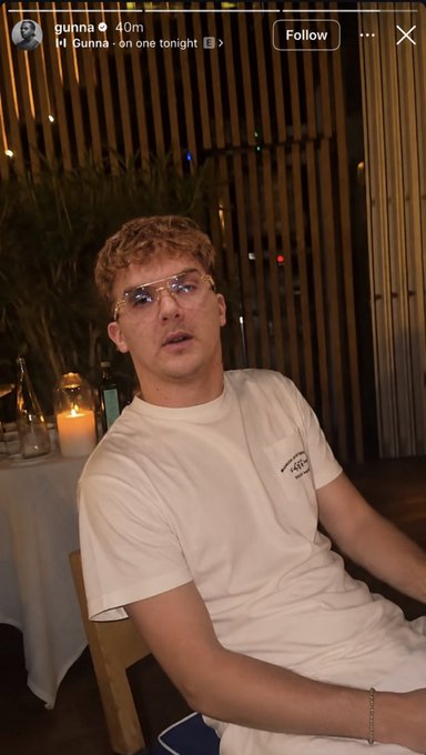 An Instagram story screenshot showing a young man with curly hair and glasses wearing a white t-shirt, with text reading "gunna 40m Hi Gunna . on one tonight >".