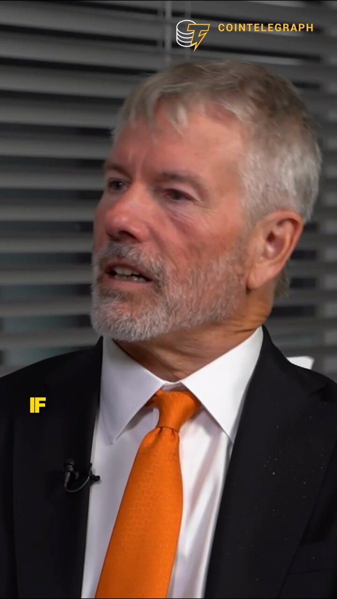 The image features a man wearing an orange tie, which appears to be a prominent feature of his outfit. He is dressed in a suit and tie, giving him a professional appearance. The background shows that he is standing next to a window with blinds, suggesting that he might be indoors or in a room with limited natural light.

The image also contains text elements such as the words "Bitcoin" and "Strategy", which could possibly be related to the Bitcoin cryptocurrency or some other topic of interest. The man's facial expression appears to convey surprise or confusion, adding an element of intrigue to the scene.