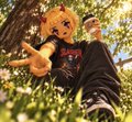 A low-angle, animated shot of a character with yellow hair holding a long object, set in a sunny outdoor environment with green grass and trees.
