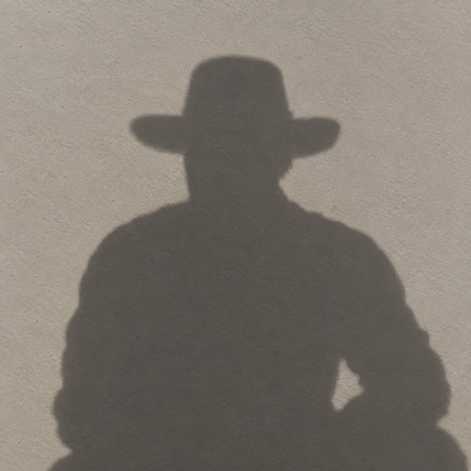A dark silhouette shadow of a person wearing a wide-brimmed hat cast on a light-colored textured wall or pavement.