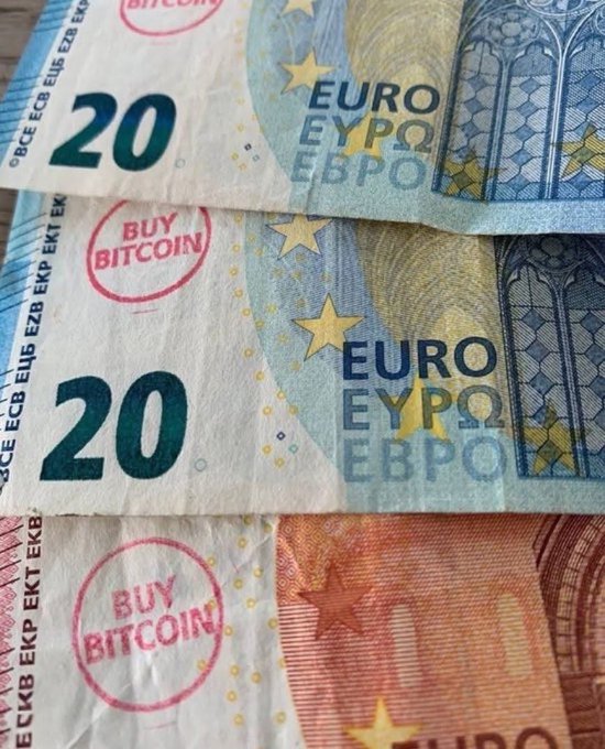 Close-up of 20 Euro banknotes stamped with red "BUY BITCOIN" circles.