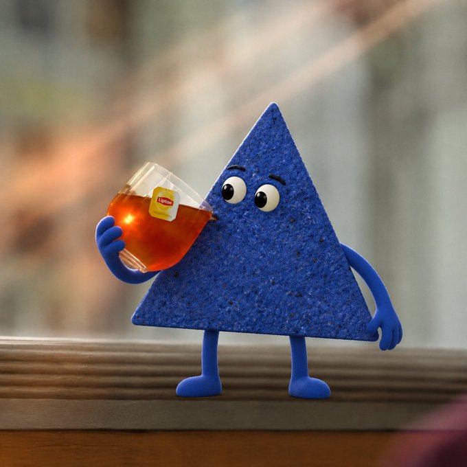 A blue triangular character with a textured surface, eyes, and small limbs stands on a windowsill holding a glass of tea with a "Lipton" label visible on the tag.