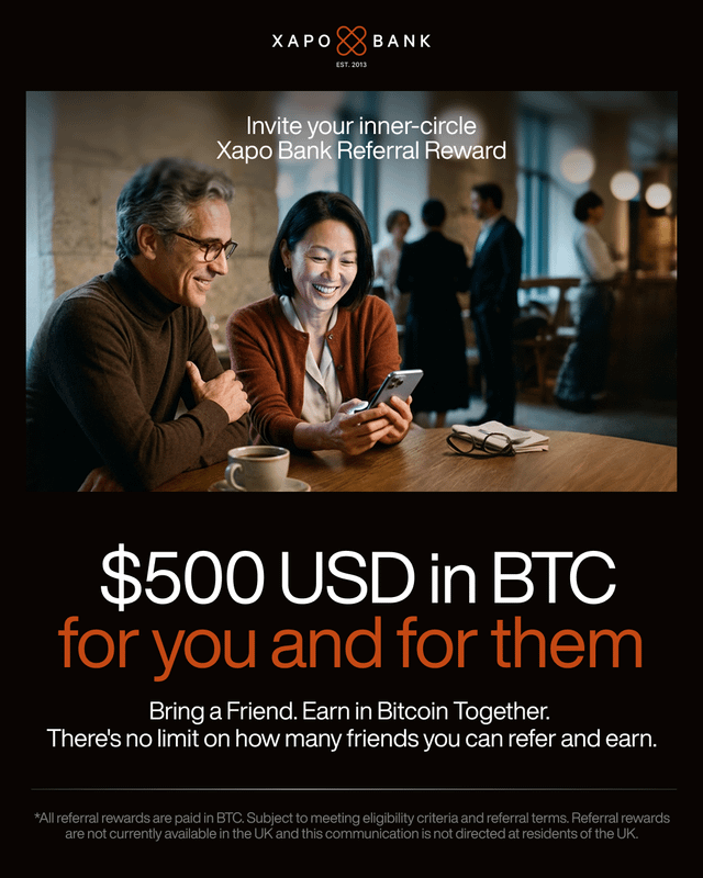 The image features a man and woman sitting at a table, looking at their phones. The text of the post suggests that they can earn $500 US Dollars (USD) by referring friends to Xapo Bank's Bitcoin rewards program. This means that if someone refers another person who then opens an account with Xapo Bank and uses Bitcoin as payment, both parties will receive $500 USD in Bitcoin.