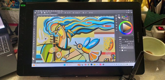 A Huion drawing tablet displaying digital artwork in progress featuring a stylized woman with flowing blue hair alongside colorful birds and abstract designs, with art software interface elements visible on the screen.