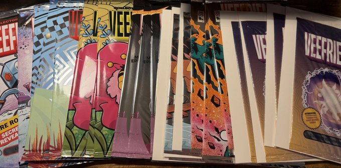 A collection of comic book issues in plastic sleeves, including titles like "X-MEN" and "VEE FRIENDS," spread out on a table.