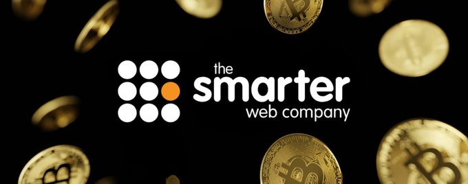 The image features "the smarter web company" logo set against a dark background filled with floating gold Bitcoin coins, visually reinforcing the company's recent announcement of purchasing 35 additional BTC for $2.7M, bringing their total holdings to 2,747 BTC.