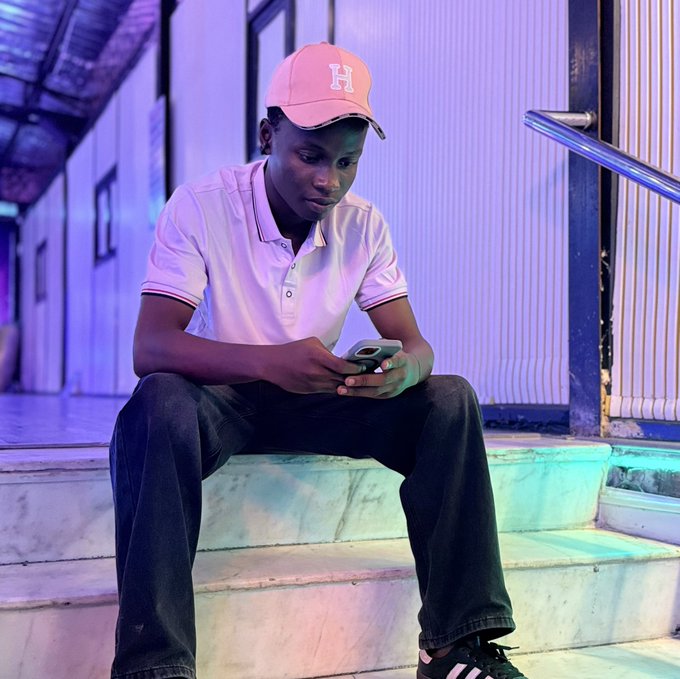 A young man wearing a pink baseball cap with an "H" logo sits on stairs, looking at his phone. The image reflects the accompanying post's sentiment of reflection and resilience after a less-than-ideal month.