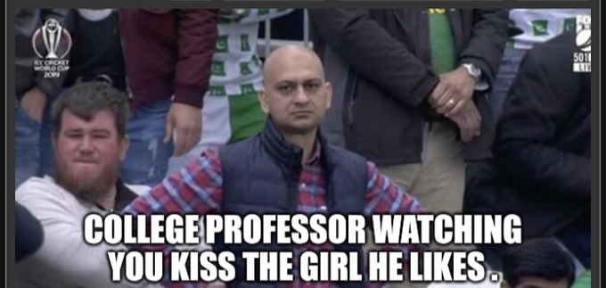 A bald man with a serious, unamused expression sits in a crowd at an ICC Cricket World Cup 2019 event, captioned "COLLEGE PROFESSOR WATCHING YOU KISS THE GIRL HE LIKES." The image humorously conveys impatience and a steely stare, humorously reflecting the Vietnamese post's anticipation for a new feature update.
