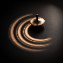 A spinning top creates glowing circular light trails against a dark background, visually echoing the post's metaphor of interconnected storage, bandwidth, and computing power orbiting a unified center like the dynamic motion of the BitTorrent ecosystem.