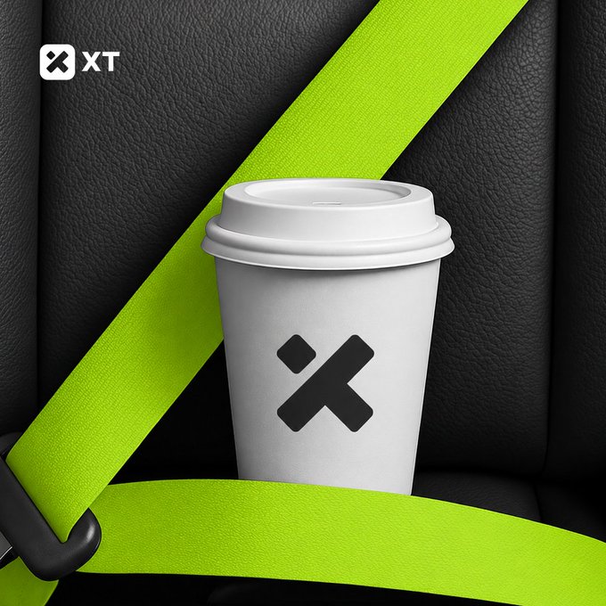 A white paper coffee cup with a black "X" logo sits secured by a neon green seatbelt against a black leather background, with an "XT" logo in the upper left corner—visually blending the concepts of morning coffee and crypto trading fuel as referenced in the post about #XTexchange.