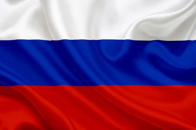 The image shows the Russian flag waving, featuring its horizontal white, blue, and red stripes. This relates to the post as it visually represents Russia, the nation now launching MOEX crypto perpetual futures for BTC, ETH, SOL, XRP, and TRON.