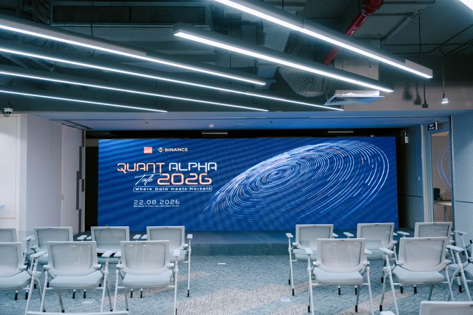 An empty conference room with rows of chairs facing a large screen displaying 'Binance Quant Alpha 2026 Where Data Meets Markets' dated 22.09.2026.