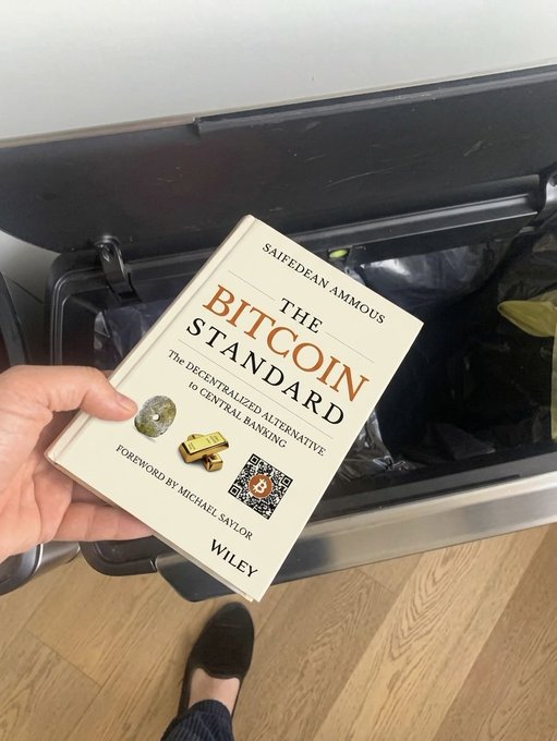 A hand holds up Saifedean Ammous's "The Bitcoin Standard" book in front of an open car trunk, fitting with Strategy's ($MSTR) announcement of its Digital Credit Capital Framework aimed at strengthening digital credit and preserving long-term Bitcoin exposure. The book's subtitle, "The Decentralized Alternative to Central Banking," underscores the Bitcoin-centered vision behind the new financial initiative.