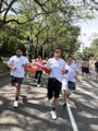 A group of people run together down a street during what appears to be a marathon or running event.