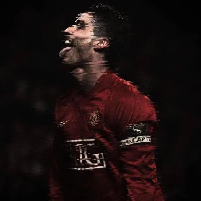 A heavily stylized, dark image of a soccer player in a red Manchester United jersey with a captain's armband, depicted with a glitch or motion-blur effect.