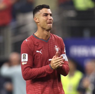 A photo of Portuguese footballer Cristiano Ronaldo wearing the Portugal national team's red Puma jersey, appearing to clap during a match.