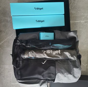 A Bitget 8th Anniversary gift box is displayed, featuring branded turquoise "Bitget" boxes atop a black mountaineering-style backpack with a removable logo panel, showcasing the company's outdoor kit as described in the post.