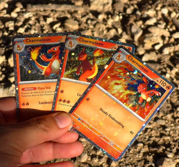 A hand holds three Pokémon trading cards (Charmeleon, Charmeleon, and Charmeleon) featuring holographic foil designs against a backdrop of rocky ground.