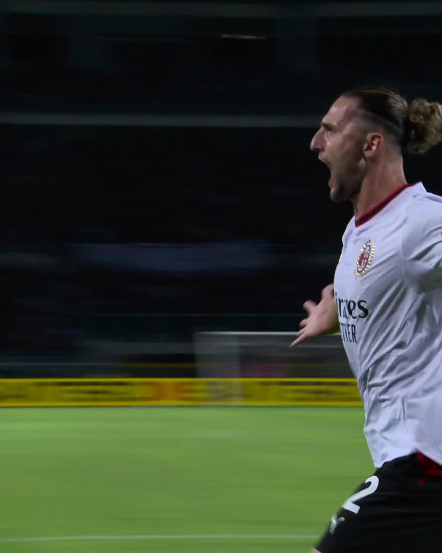 Adrien Rabiot, wearing AC Milan's white away jersey with the number 2, celebrates on the pitch with an emotional shout, likely reacting to a goal or assist. His passionate expression fits with his strong performance, having contributed both a goal and an assist for manager Ruben Amorim.