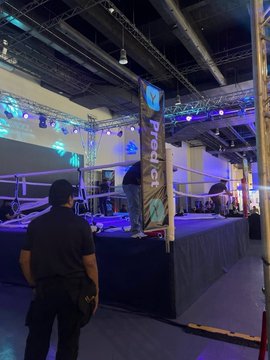 The image shows a wrestling ring set up at an event venue, with a banner prominently displaying "Protocol" hanging from the ropes while a man in a black shirt stands with his back to the camera. The post's caption about "Predict Protocol x Philippines Week" reflects the event shown, capturing the lively gathering where the community came together to celebrate and connect at this sponsored wrestling-themed event.