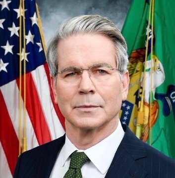 An official portrait of Federal Reserve Chairman Jerome Powell wearing glasses and a dark suit with a green tie, standing in front of the American flag and another green flag.