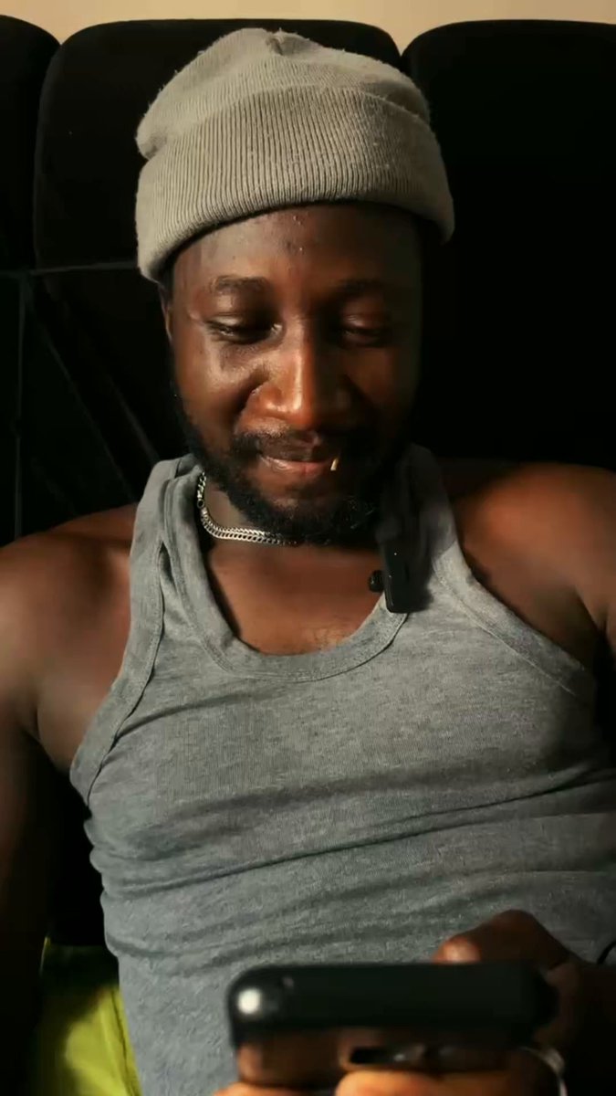 The image shows a man wearing a gray beanie sitting down with his hands on a cell phone. The photo has been edited to focus solely on the man's face, while the background appears to be a black chair or couch. The caption provided seems unrelated to the main subject and does not provide any context about the content of the image.