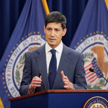 A man in a dark suit and tie speaks at a podium with the Federal Reserve seal visible behind him. The image appears to relate to Federal Reserve policy, specifically the Treasury bill purchases and liquidity measures mentioned in the post.