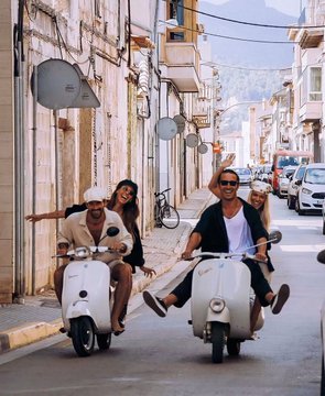 Two friends cruise down a sun-drenched Mediterranean street on matching white Vespa scooters, dressed in summer attire and sunglasses, smiling as they ride past pastel buildings toward the coastline.

The image perfectly captures the post's carefree message—instead of stressing over Bitcoin's volatile charts, two people embrace a relaxed, steady lifestyle (symbolizing dollar-cost averaging with regular "dips" into fun) by enjoying simple summer pleasures like scooter rides along a coastal town.