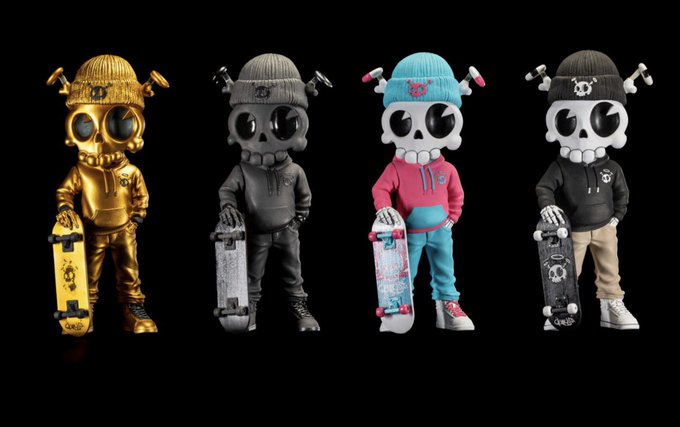 Four designer figurines in gold, dark grey, pink/blue, and black hoodies stand in a row holding skateboards against a black background.