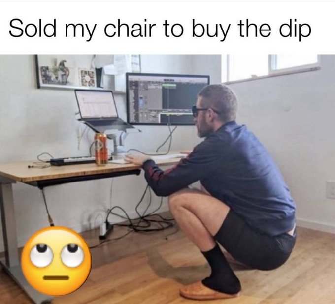 A humorous meme showing a man squatting on the floor using a standing desk setup with multiple monitors, captioned 'Sold my chair to buy the dip,' featuring a pleading face emoji.