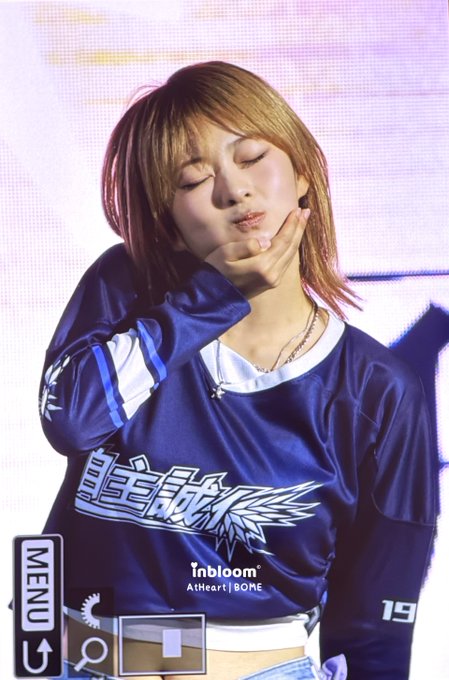 A young woman with short reddish-brown hair poses with her eyes closed and hand under her chin, wearing a navy blue long-sleeve jersey featuring "inbloom," "AtHeart," "BOME," and the number "19." The image aligns with the post about a Sungshin Women's University preview, showcasing a member of the group AtHeart (BOME) at the event.