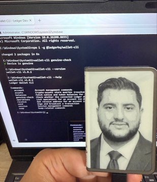 A hand holds a Ledger hardware wallet displaying a black-and-white portrait of a bearded man in a suit and tie, positioned in front of a laptop screen showing a Windows command prompt with text including "User@WIN-Desktop" and references to wallet-cli tools. The image visually reinforces the post's message about maintaining human-controlled security boundaries in crypto, as the Ledger device represents the physical, user-approved checkpoint between AI agents and financial actions.