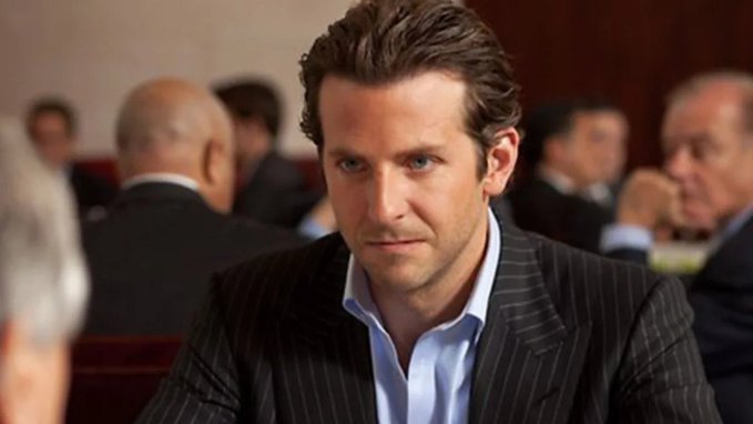 A well-dressed man in a pinstripe suit sits in what appears to be a formal setting, giving a confident side glance. The image's smug, scheming expression visually conveys the shrewdness behind the accompanying advice to buy Bitcoin at $100k+ and sell at $65k—a classic "market manipulation" or insider trading vibe.